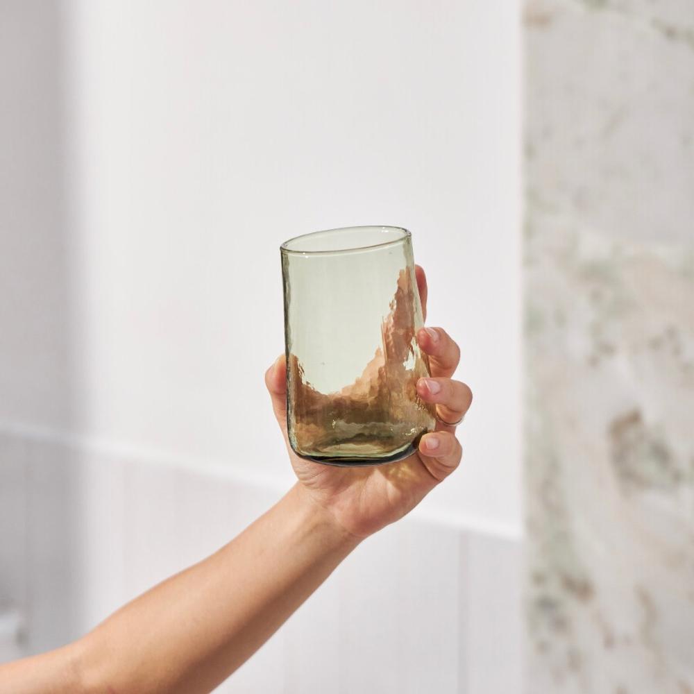 Hand holding a tall green drinking glass